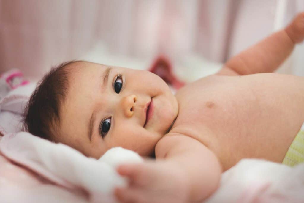 An infant lying on a soft surface looking at the camera with a slightly curious expression, symbolizing hope in fertility discussions.
