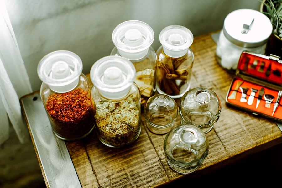 Glass jars filled with dried herbs and cupping tools on a wooden surface at Willow Tree Clinic in Portland, OR, where custom herbal formulas are used alongside acupuncture to support fertility naturally.