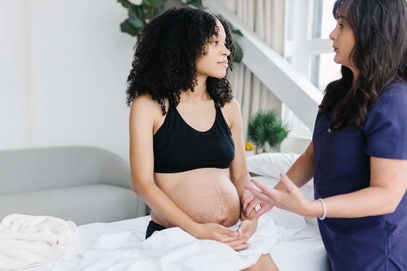 A healthcare professional in Portland, Oregon is having a conversation with a pregnant woman during a pregnancy care check-up.