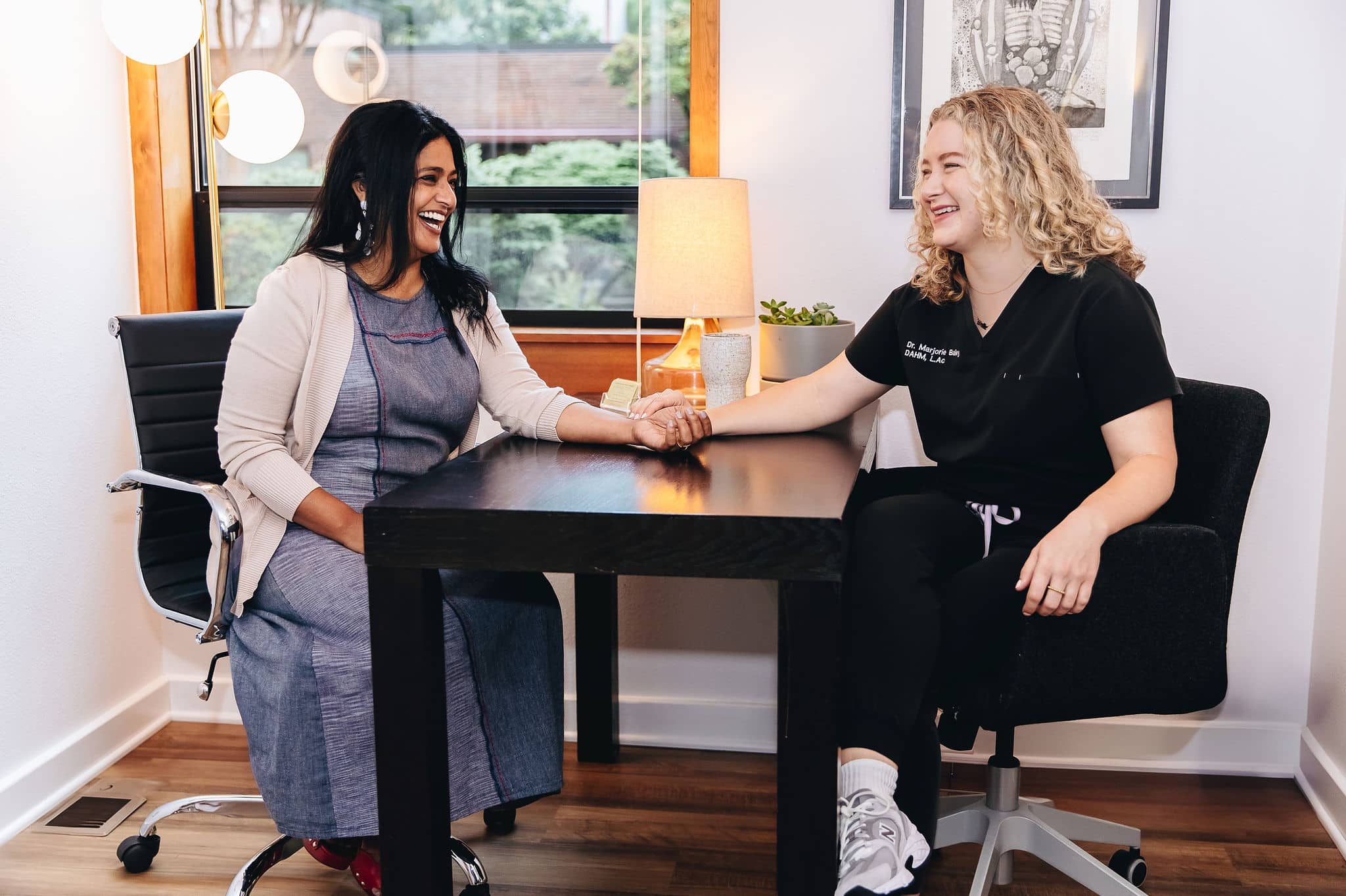 a woman sitting at a table holding a woman's hand