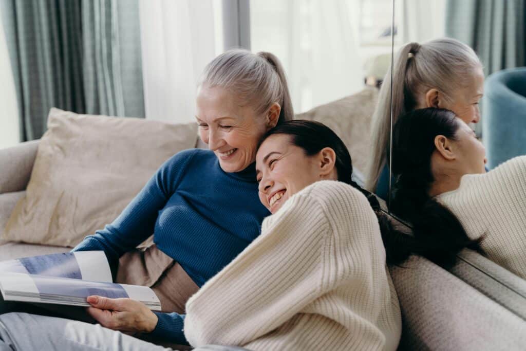 Two middle-age women smiling and laughing on a couch