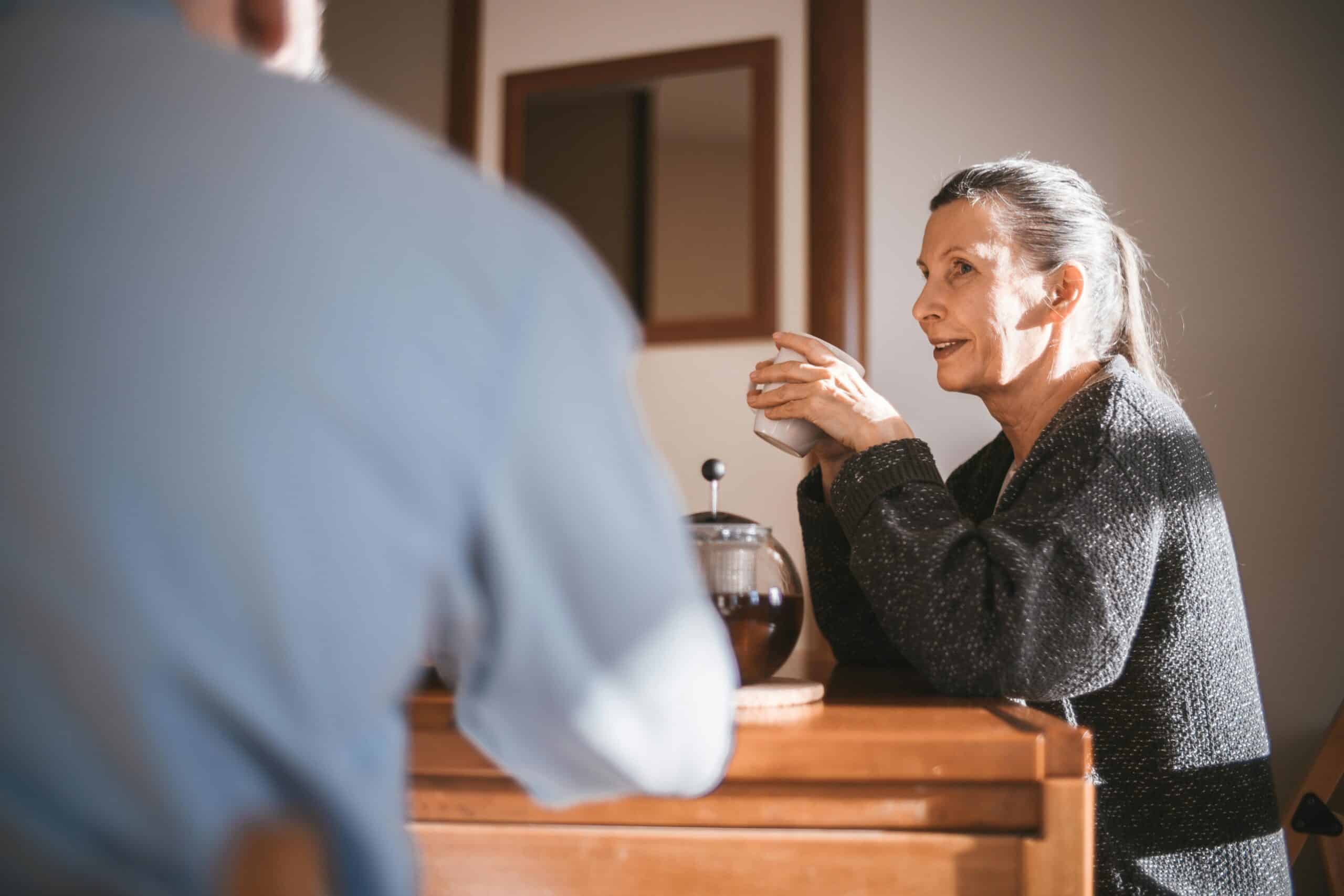 Woman smiling and drinking tea after dealing with perimenopause digestive issues