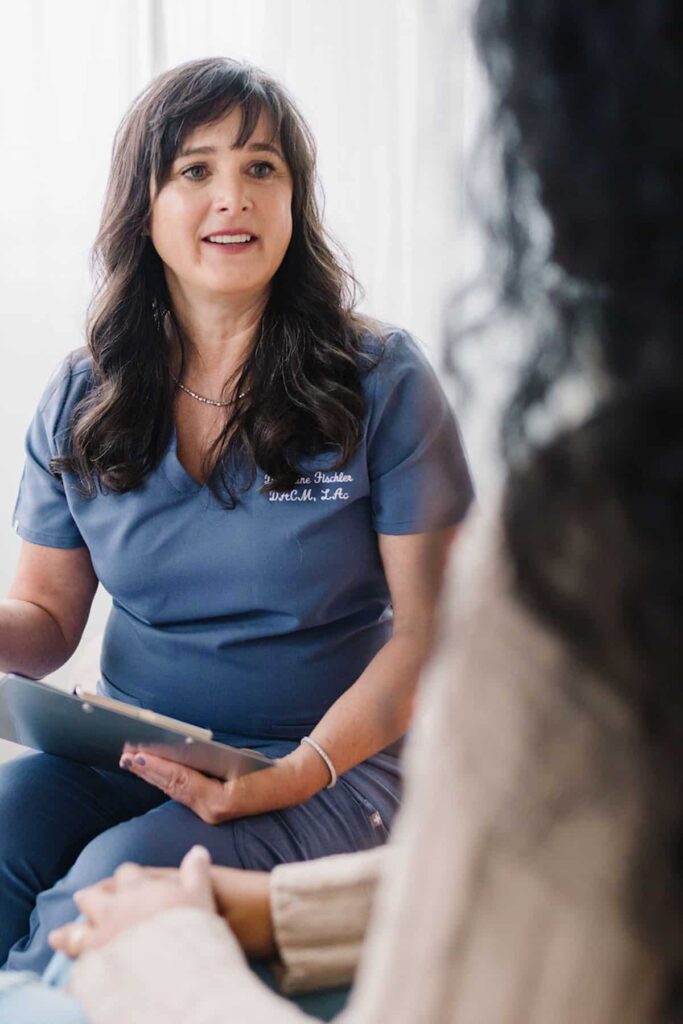 Dr. Kiné Fischler, DACM talks to female patient about what causes sciatic nerve pain.