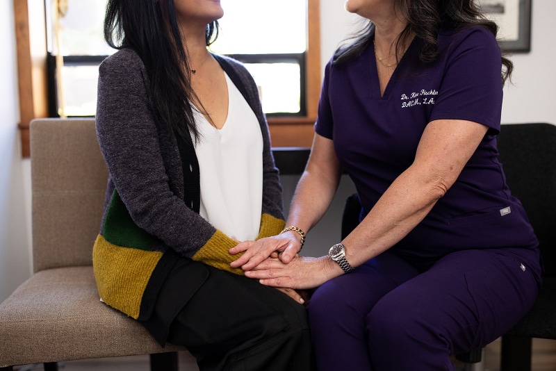 Practitioner holding a patient's hands during a comforting consultation at Willow Tree Clinic, showing warmth and connection.